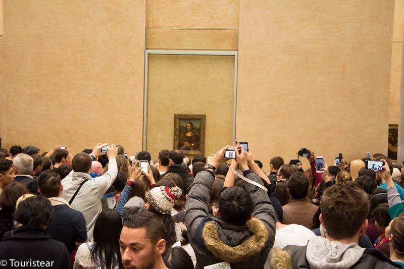 una manada de gente haciendo una foto de la Monalisa durante las vacaciones en Londres París