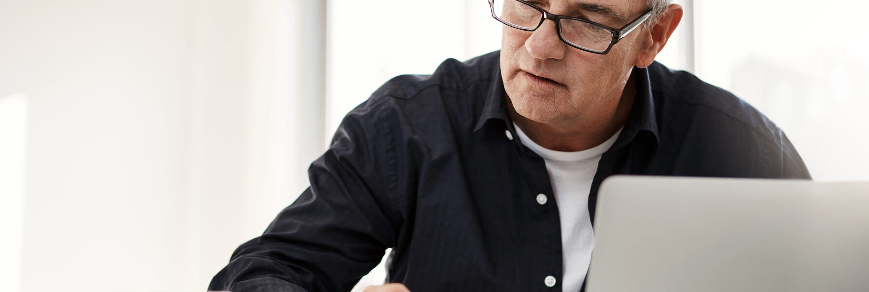 Man on laptop at desk checking papers