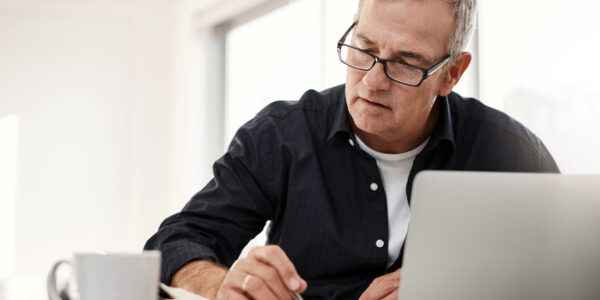 Man on laptop at desk checking papers