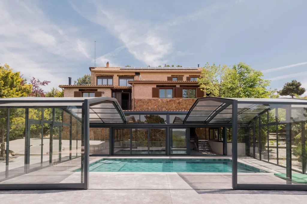 Piscina cubierta con casa rural al fondo
