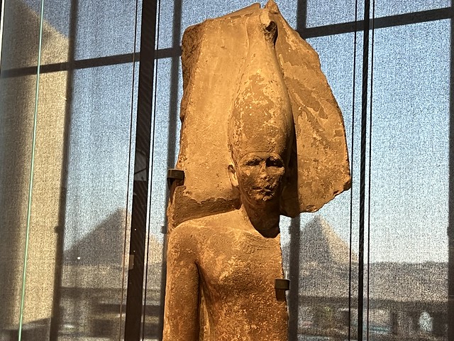 Estatua exhibida en el Gran Museo Egipcio (GEM) con las pirámides de Guiza al fondo