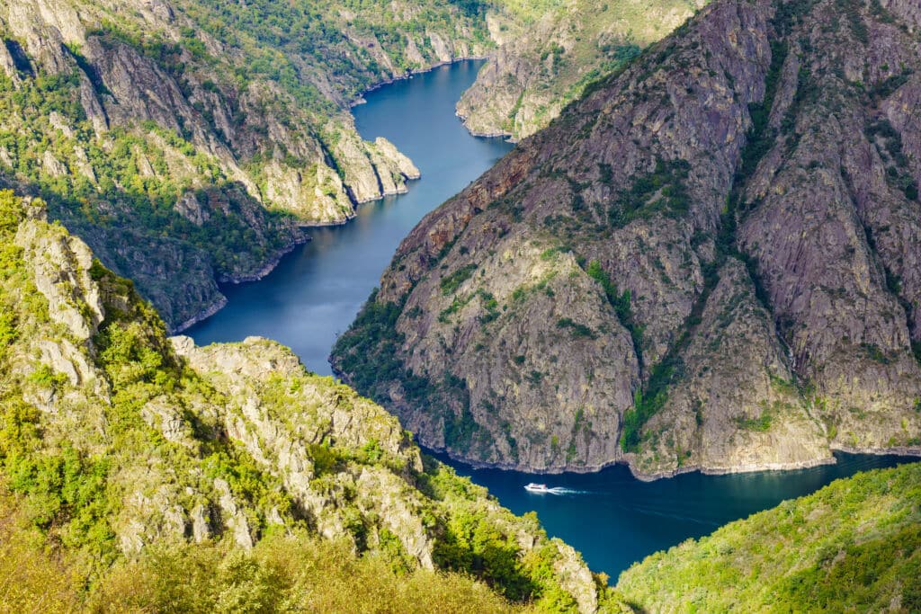 Un barco pasando por un cañón del río Sil, en la Ribeira Sacra. Por anetlanda