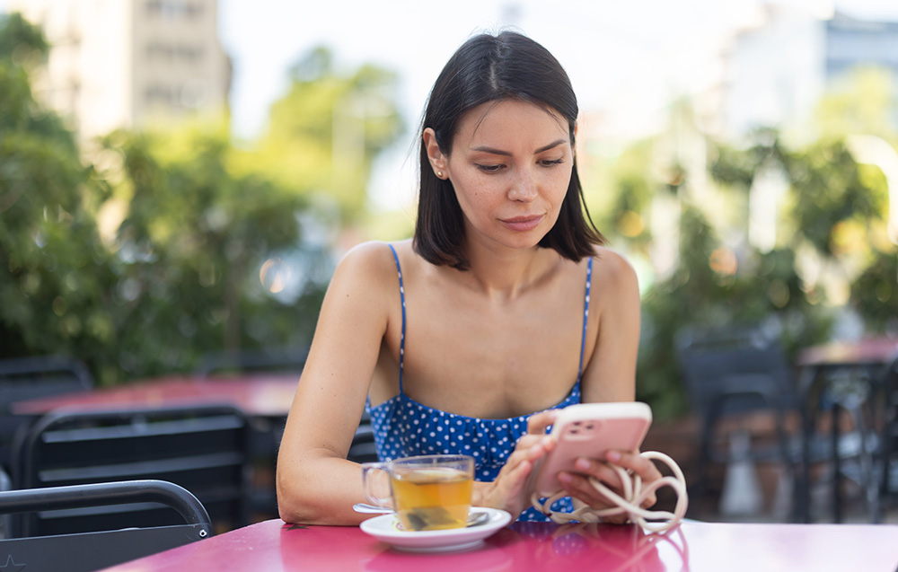 Adult woman with phone drinking tea in cafe