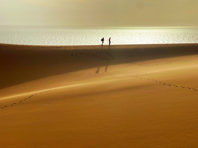 Caminando en las dunas del desierto del Namib con el océano de fondo (Baía dos Tigres, Angola)